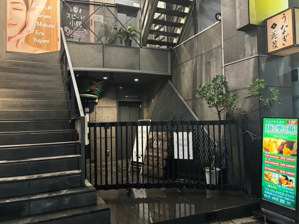 야간에 1층 엘리베이터 앞이 검은 셔터로 닫혀 있고, 왼쪽에 2층으로 올라가는 계단