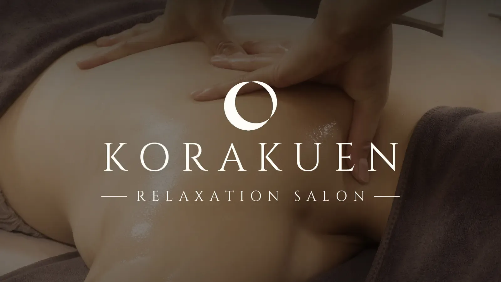 The KORAKUEN logo over a photo of hands working on an oiled back